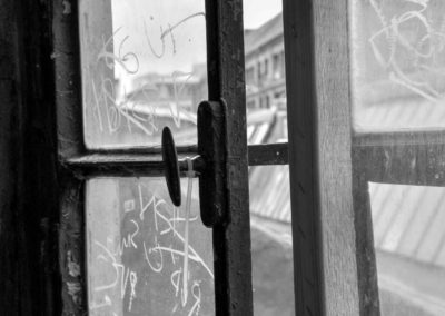 Photo noir et blanc représentant une petite fenêtre entre-ouverte du complexe de l’Arena. Artiste, Martes Martes. Lieu, Berlin.