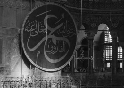 Photo noir et blanc représentant un texte religieux inscrit sur un immense panneau de bois. Artiste, Martes Martes. Lieu, Istanbul.