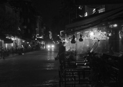 Photo noir et blanc représentant une rue de nuit avec un homme à l’entrée d’un bar. Artiste, Martes Martes. Lieu, Istanbul.